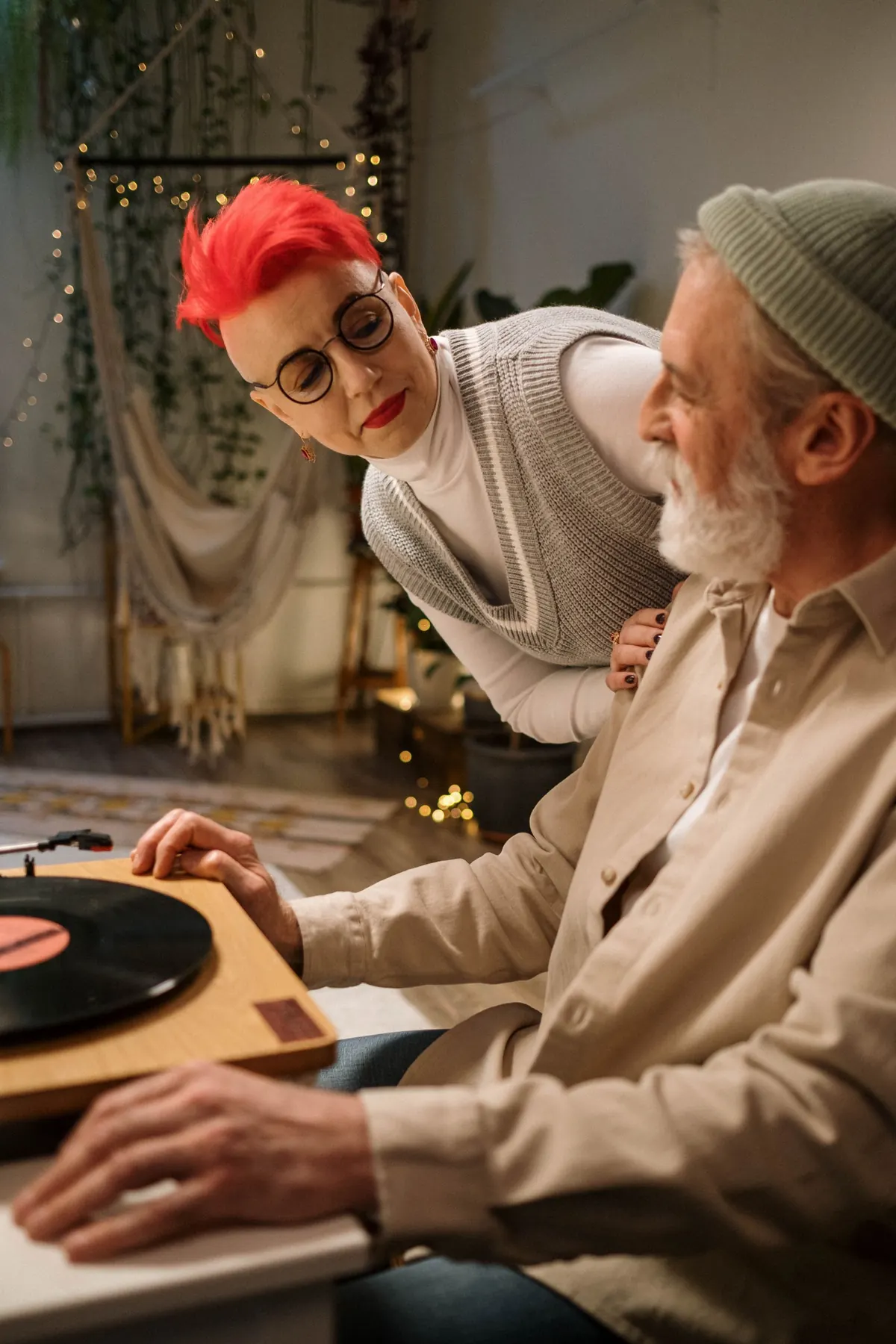 A woman smiles at her partner beside a record player.