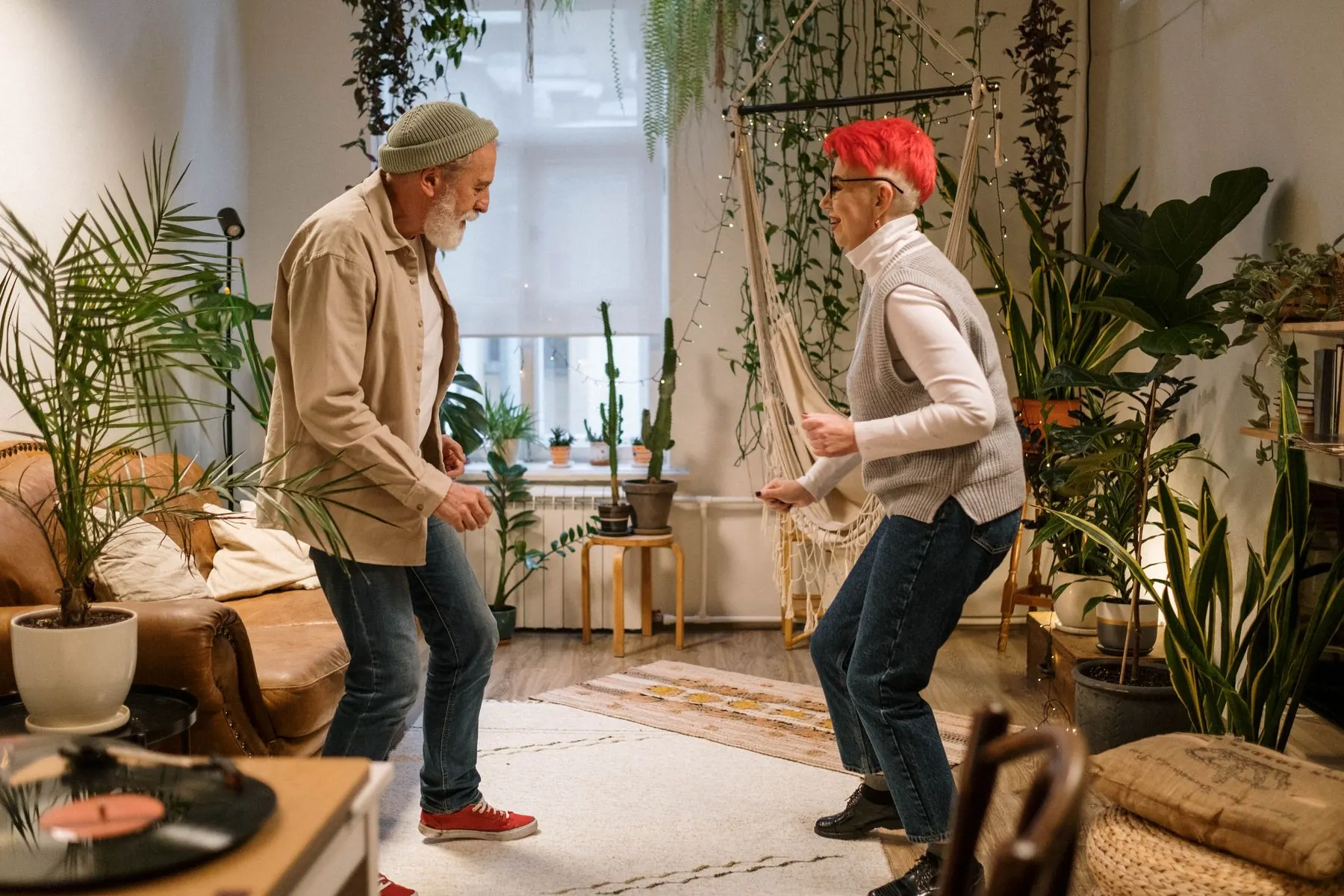 A couple laughs while dancing at home.