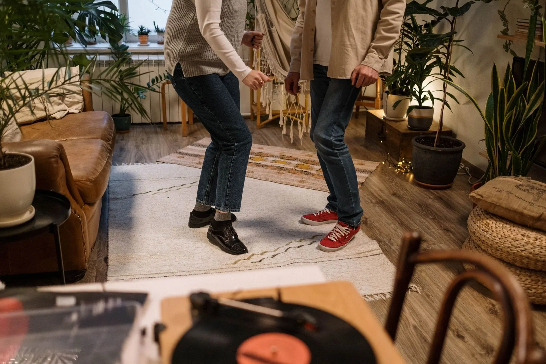 Dancing feet pass a turntable and a small stack of records.