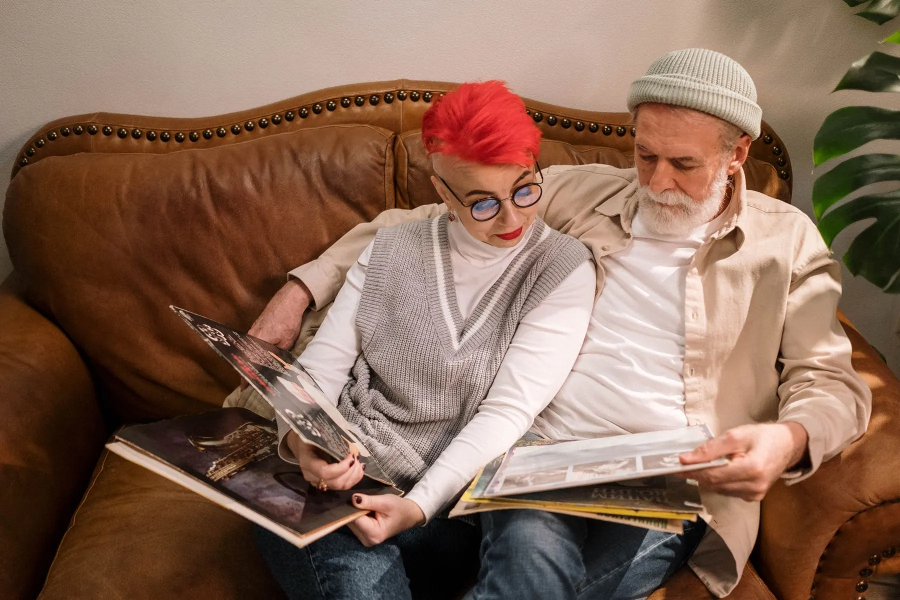 A couple looks through a photo album together on a couch.