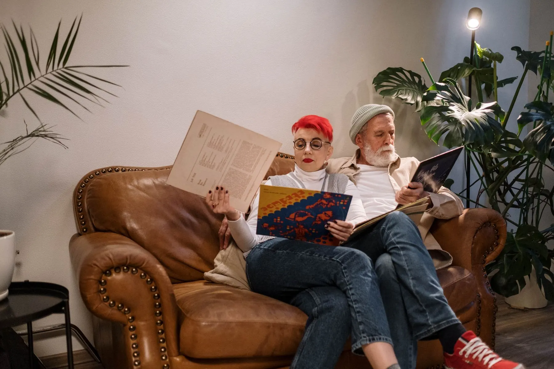 A couple sits close together while looking at a vinyl record.